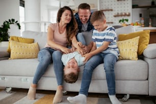 Young family enjoying at home. Happy parents tickling their son.