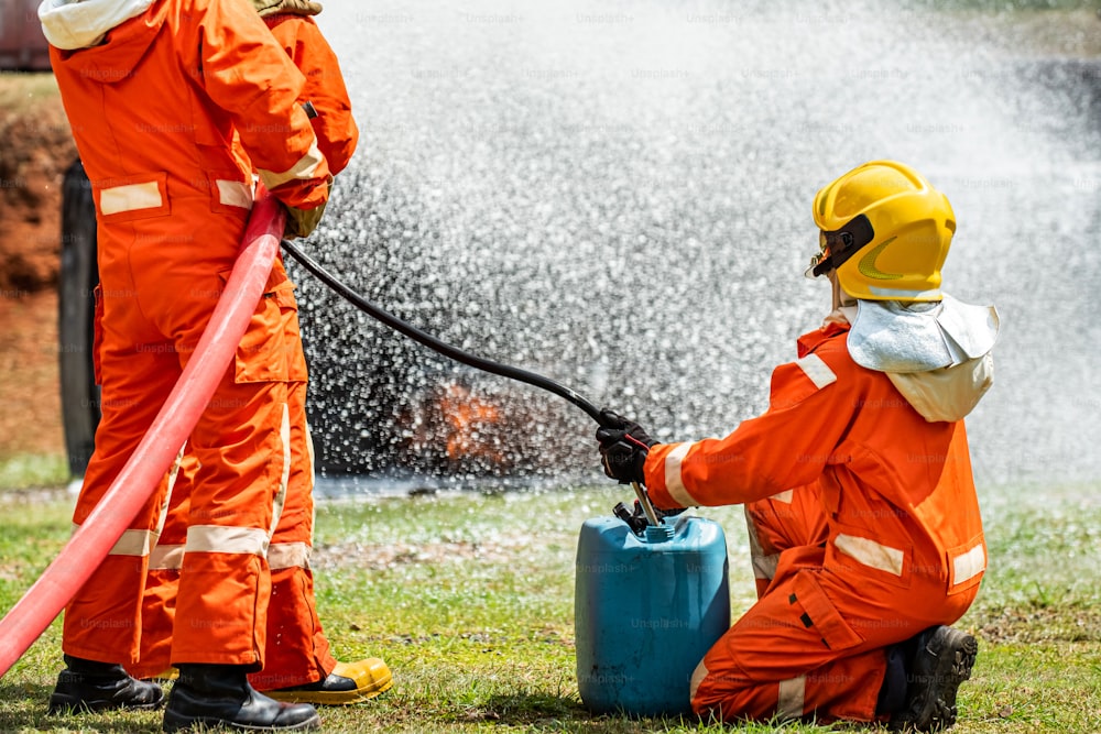 Grupo de trabajo en equipo de bomberos que utiliza agua y espuma química que rocía llamas de fuego en locales en llamas.