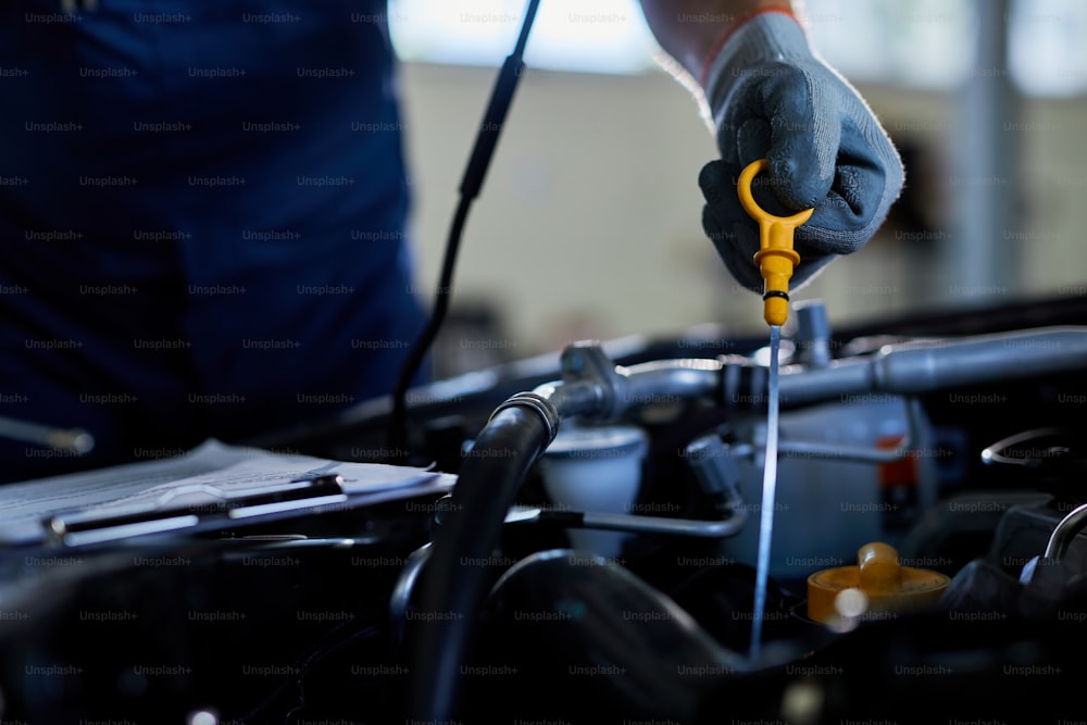 Close-up of a mechanic checking car oil in auto repair shop.