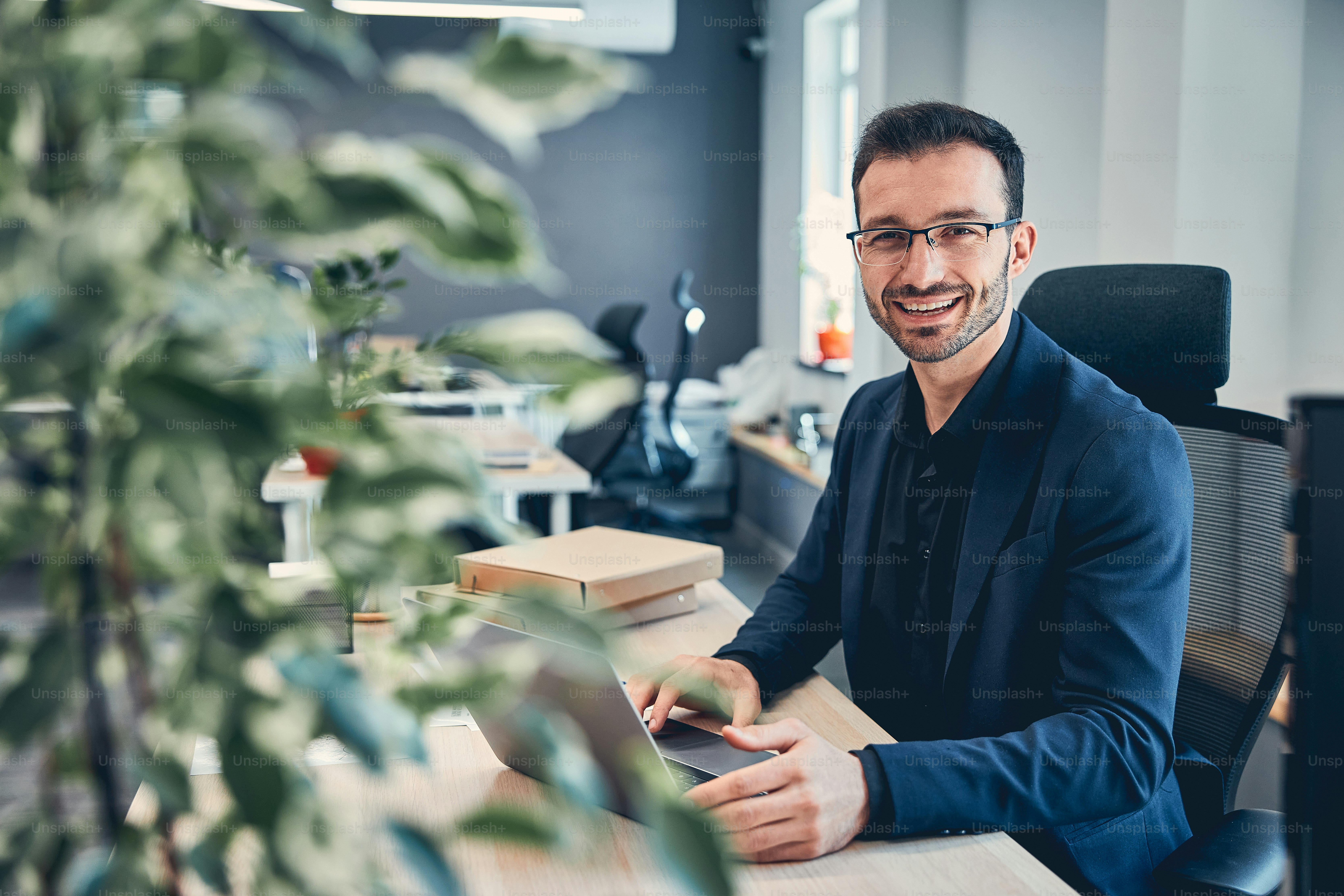 Young handsome man wearing glasses in the blue suit working at the desk ...