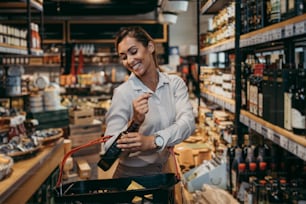 Beautiful young and elegant woman buying some healthy food and drink in modern supermarket or grocery store. Lifestyle and consumerism concept.