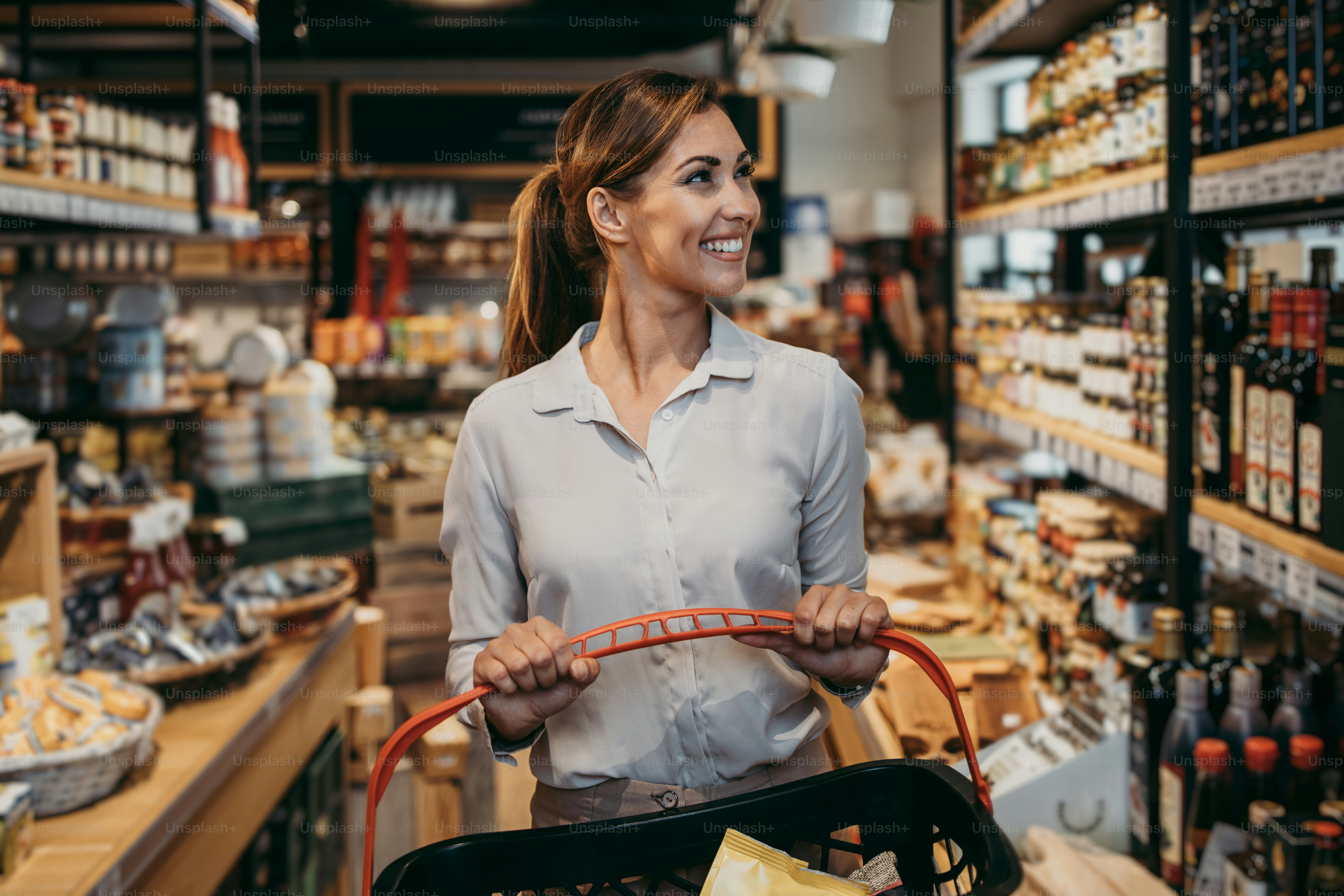 Beautiful young and elegant woman buying some healthy food and drink in modern supermarket or grocery store. Lifestyle and consumerism concept.