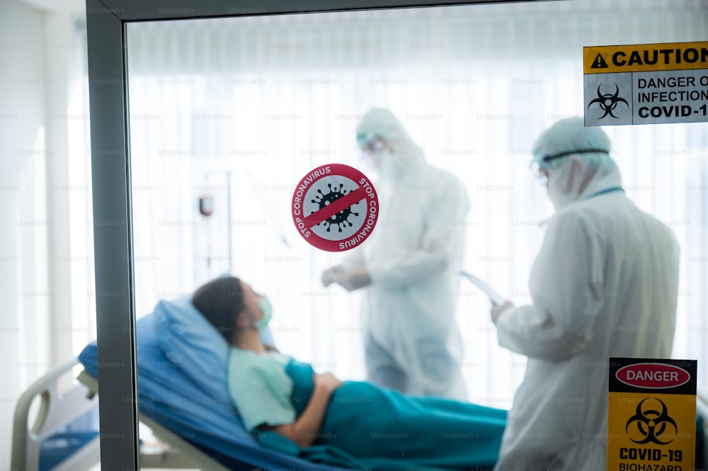 바이러스 통제 전문가 코로나 바이러스로 질병 치료를 위해 일하는 PPE 정장을 입은 의사 COVID-19 감염 환자 병원 격리실에 있는 사람들 음압실, 발병 경고 표시