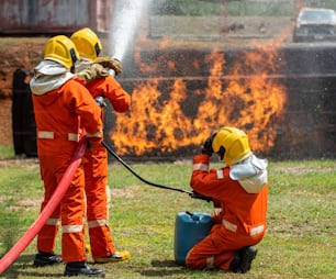 燃えている敷地内で水と化学泡を使って火炎を噴射する消防士のチームワークのグループ。