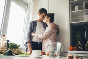 Lovely caucasian couple in the kitchen embracing while prepare food together
