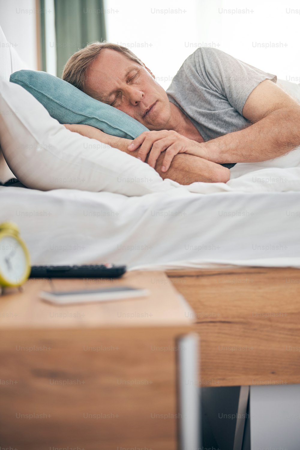 Relaxed adult man embracing his pillow while enjoying his cozy sleep in bed at home
