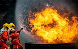 Dois bombeiros em equipe em traje de incêndio com equipamento de combate a incêndio usando água de alta pressão combater um incêndio