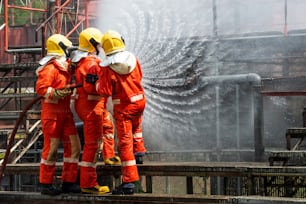 Group of Firefighter teamwork in fire suit with fire fighting equipment using high pressure water fight a fire