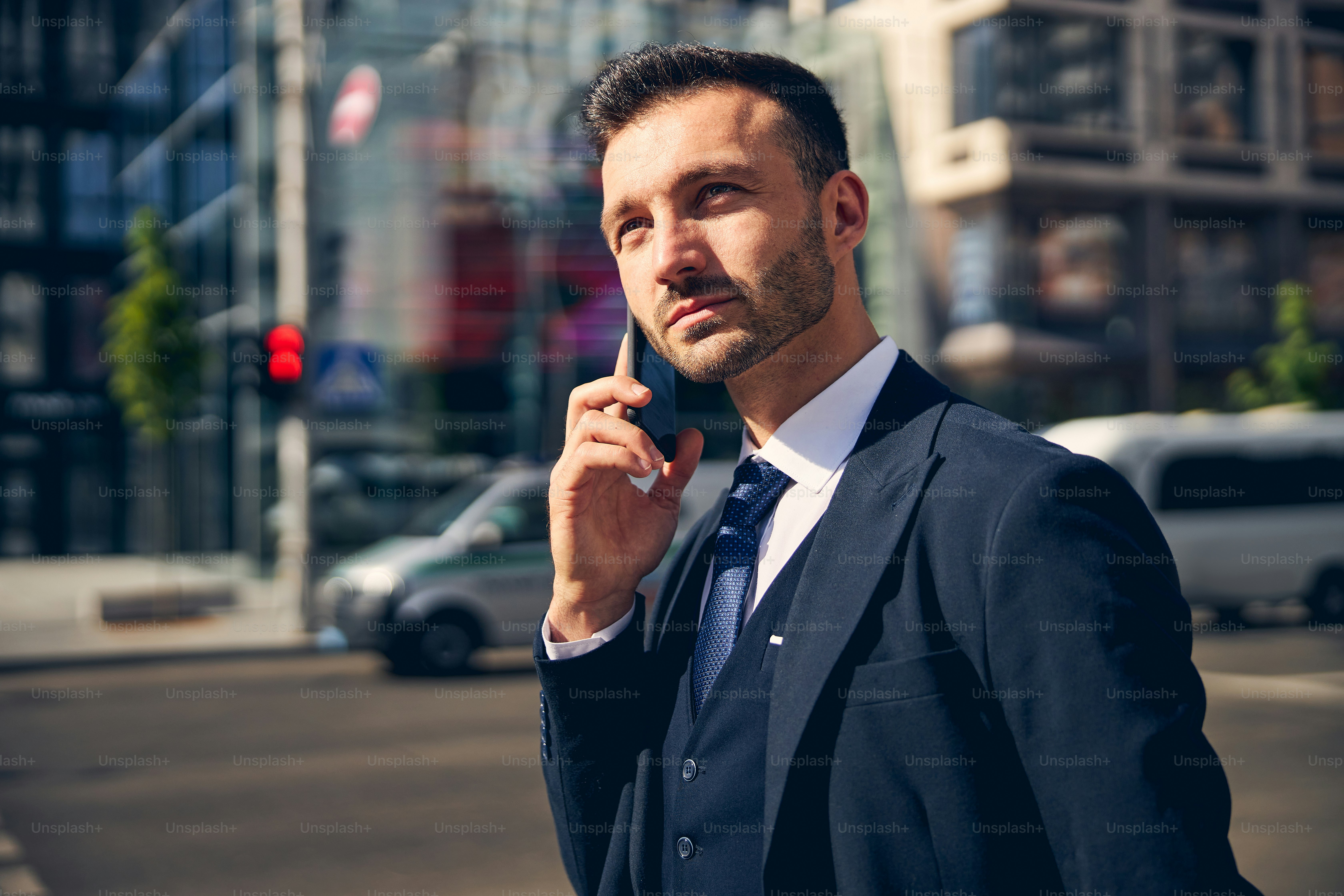 Uomo bello in piedi sullo sfondo del moderno centro d'affari e che parla al telefono durante la passeggiata