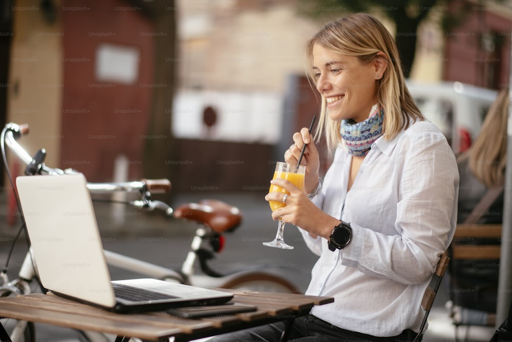 Young beautiful woman in cafe working on computer. Beautiful businesswoman working outdoors.
