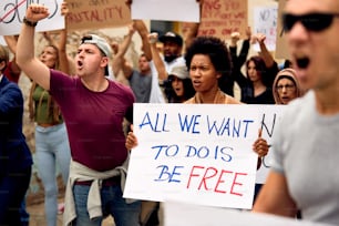 Multitud multiétnica de personas que protestaban por los derechos humanos en las calles de la ciudad. La atención se centra en una mujer negra que sostiene un cartel con la inscripción de la libertad.