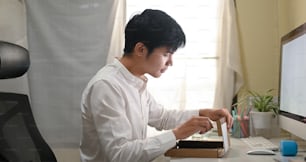 A smart man is unboxing a cardboard box from shopping online at the white working desk.