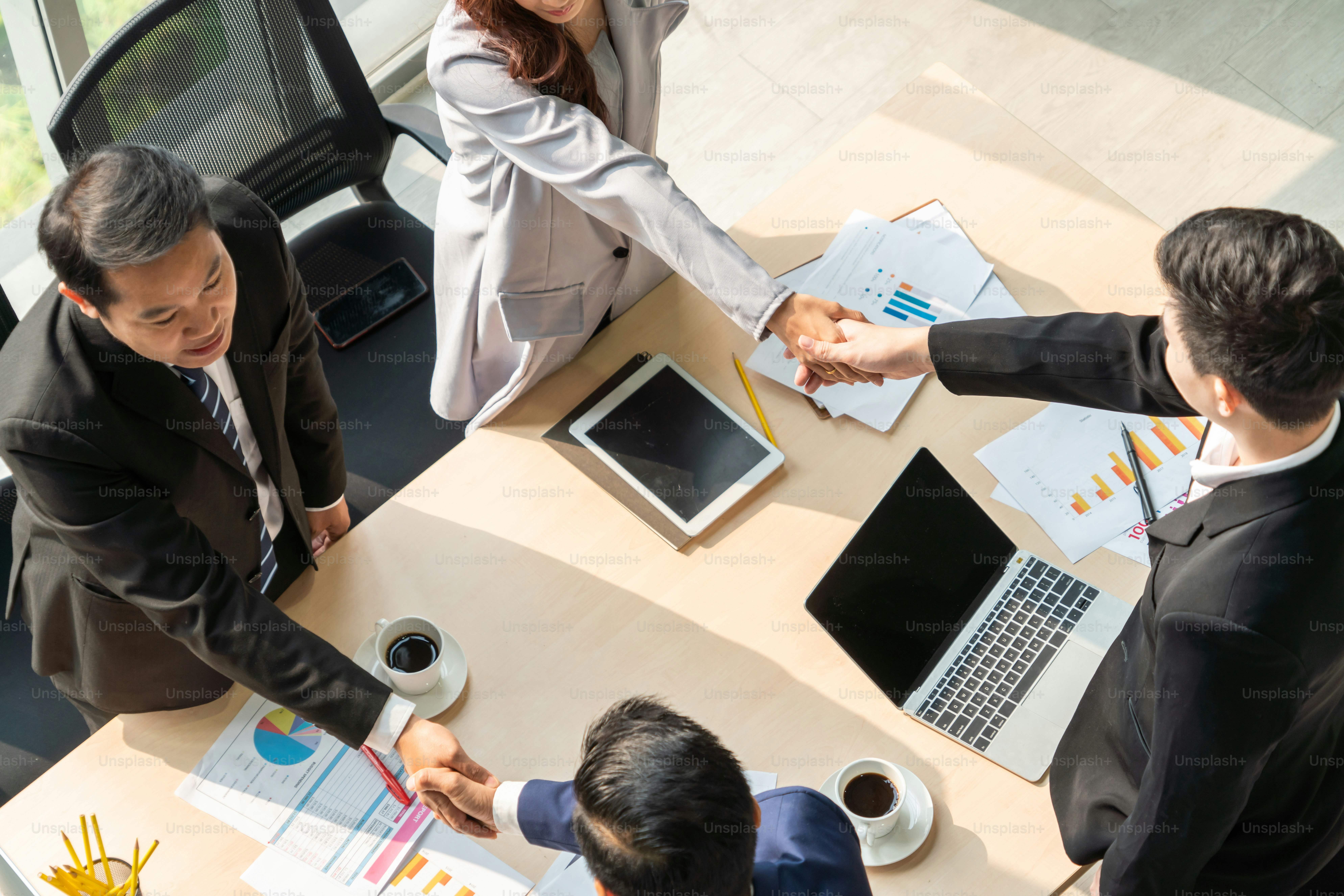 Group business people handshake at meeting table in office together with confident shot from top view . Young businessman and businesswoman workers express agreement of investment deal.