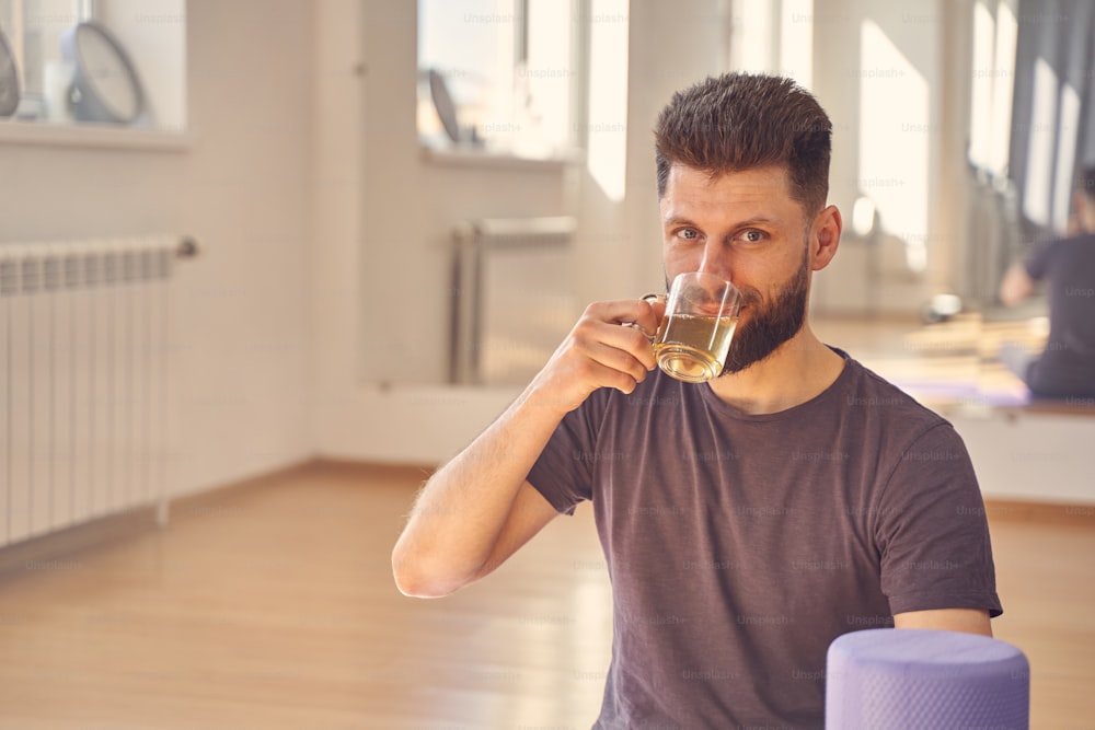 Handsome male in shirt enjoying hot beverage and looking at camera