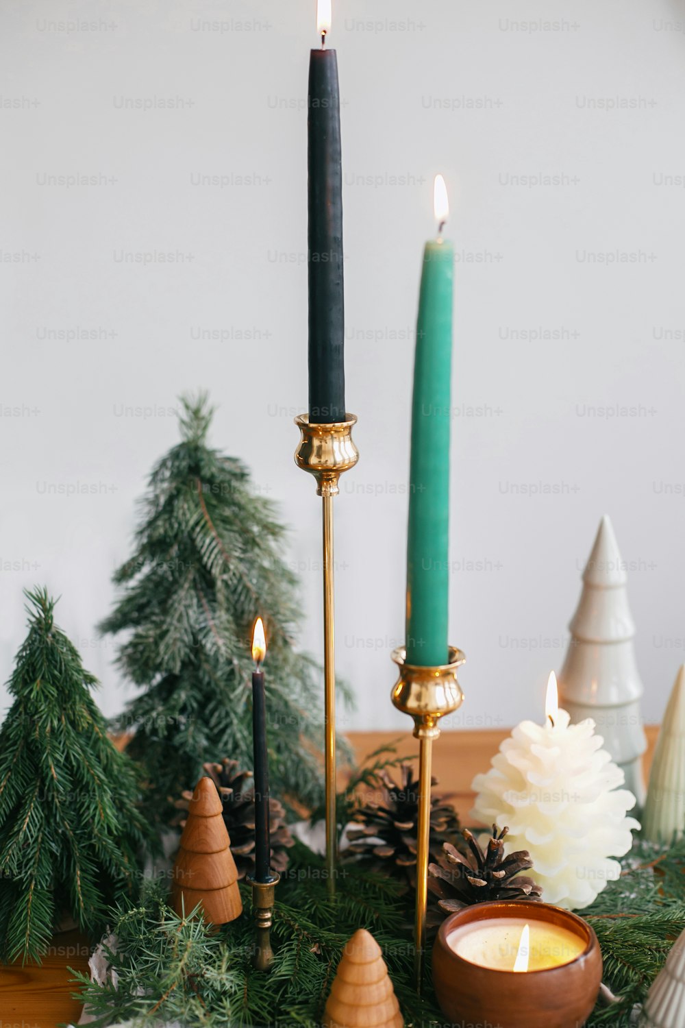 Árboles de Navidad, velas y piñas sobre tela rústica sobre mesa de madera. Decoración moderna y festiva, residuo cero. Pinos en miniatura de madera y hechos a mano.  Felices Fiestas