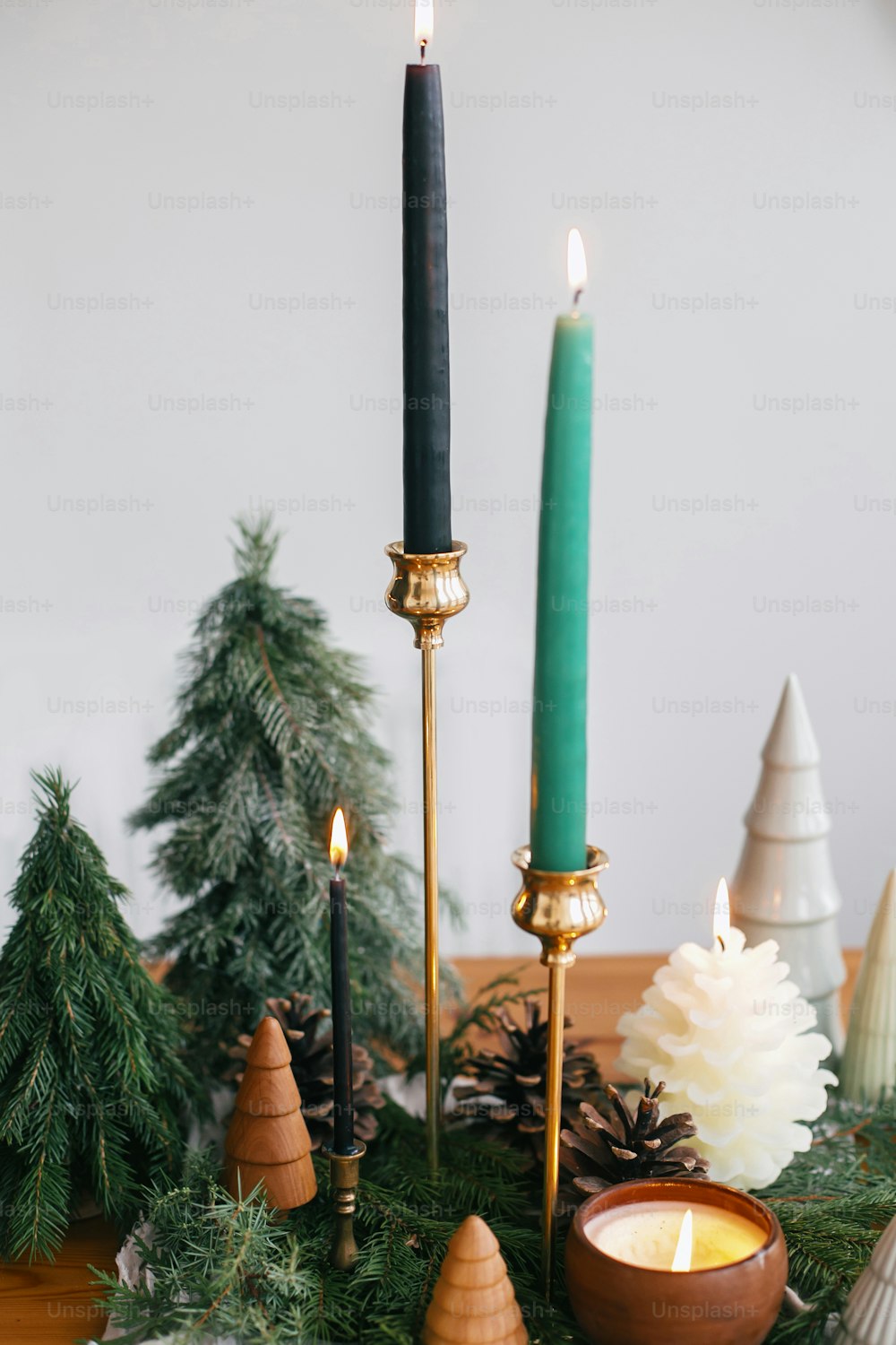 Christmas trees, candles and pine cones on rustic fabric on wooden table. Festive modern decor, zero waste. Miniature wooden and handmade pine trees.  Happy holidays