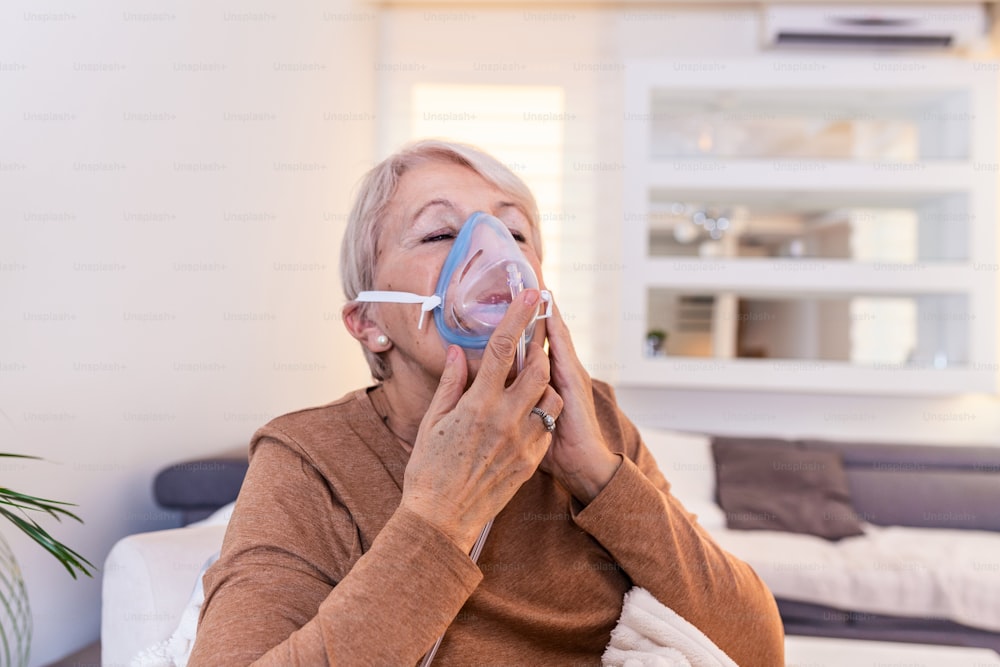 酸素マスクを吸入している病気の高齢女性、肺炎コロナウイルスのパンデミック。酸素マスクを着用し、治療を受けている病気の高齢女性。COVID19の高齢女性