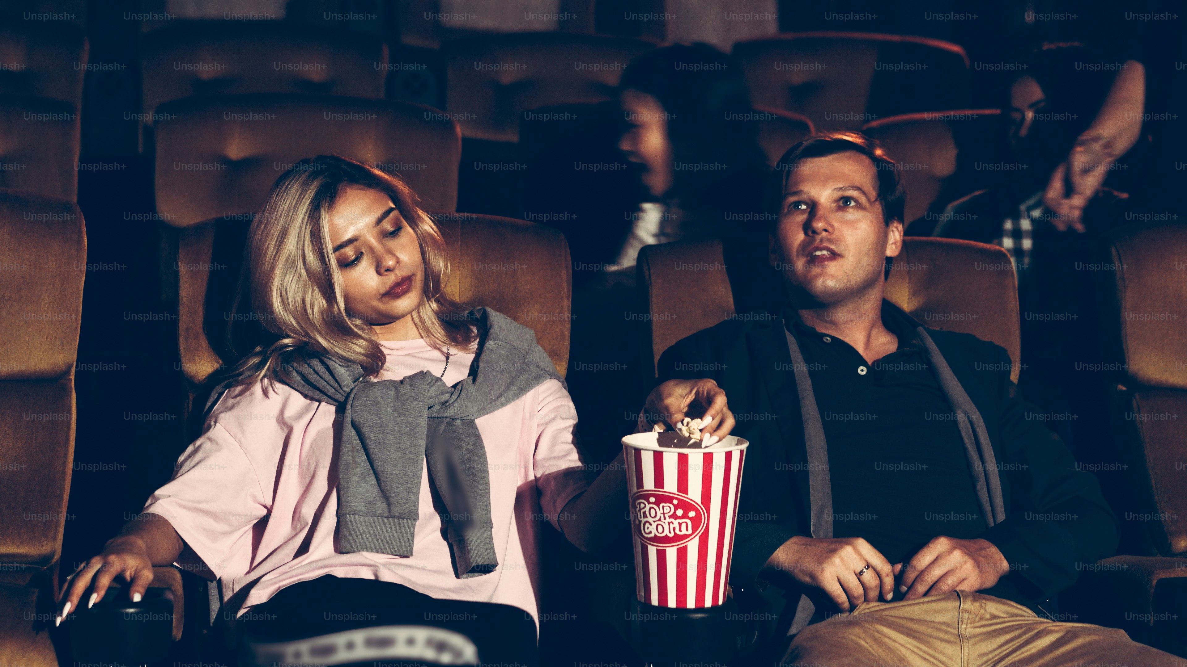 Das Publikum geht zu den Plätzen im Kino, schaut Filme und isst Popcorn.