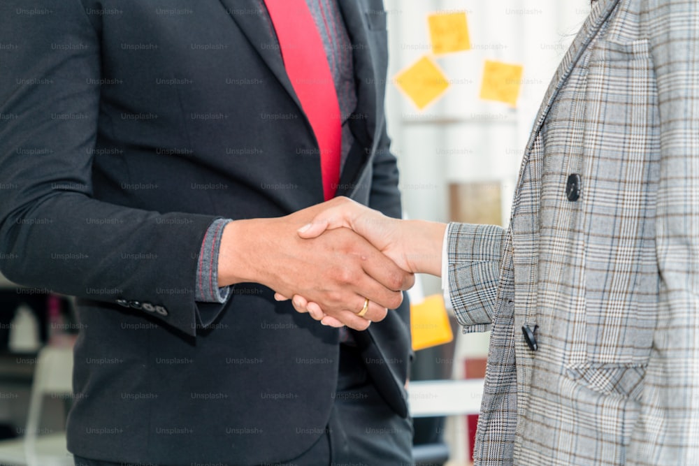 Business people handshake in corporate office showing professional agreement on a financial deal contract.