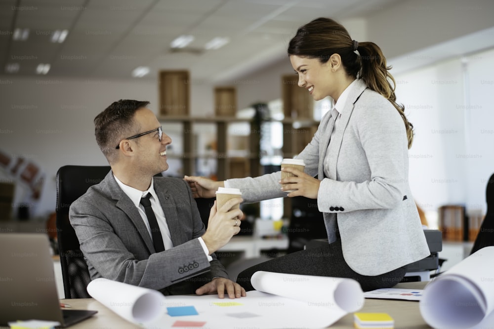 Businessman and businesswoman drinking coffee while working on the project. Young man and woman working together in the office.