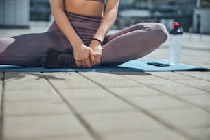 Cropped photo of a svelte young Caucasian female yogi in active wear sitting on a mat