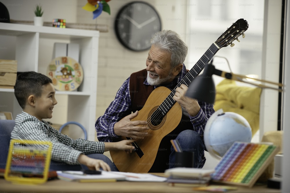 Grandfather and grandson playing guitar. Grandfather and grandson enjoying at home.