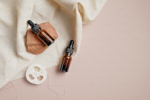 Essential oil bottles and loofah on brown background with beige fabric. Body treatment concept. Flat lay, top view.