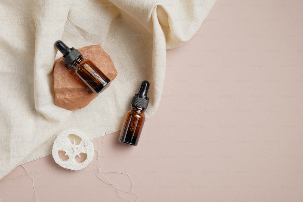 Essential oil bottles and loofah on brown background with beige fabric. Body treatment concept. Flat lay, top view.