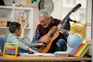 Grandfather and grandson playing guitar. Grandfather and grandson enjoying at home.