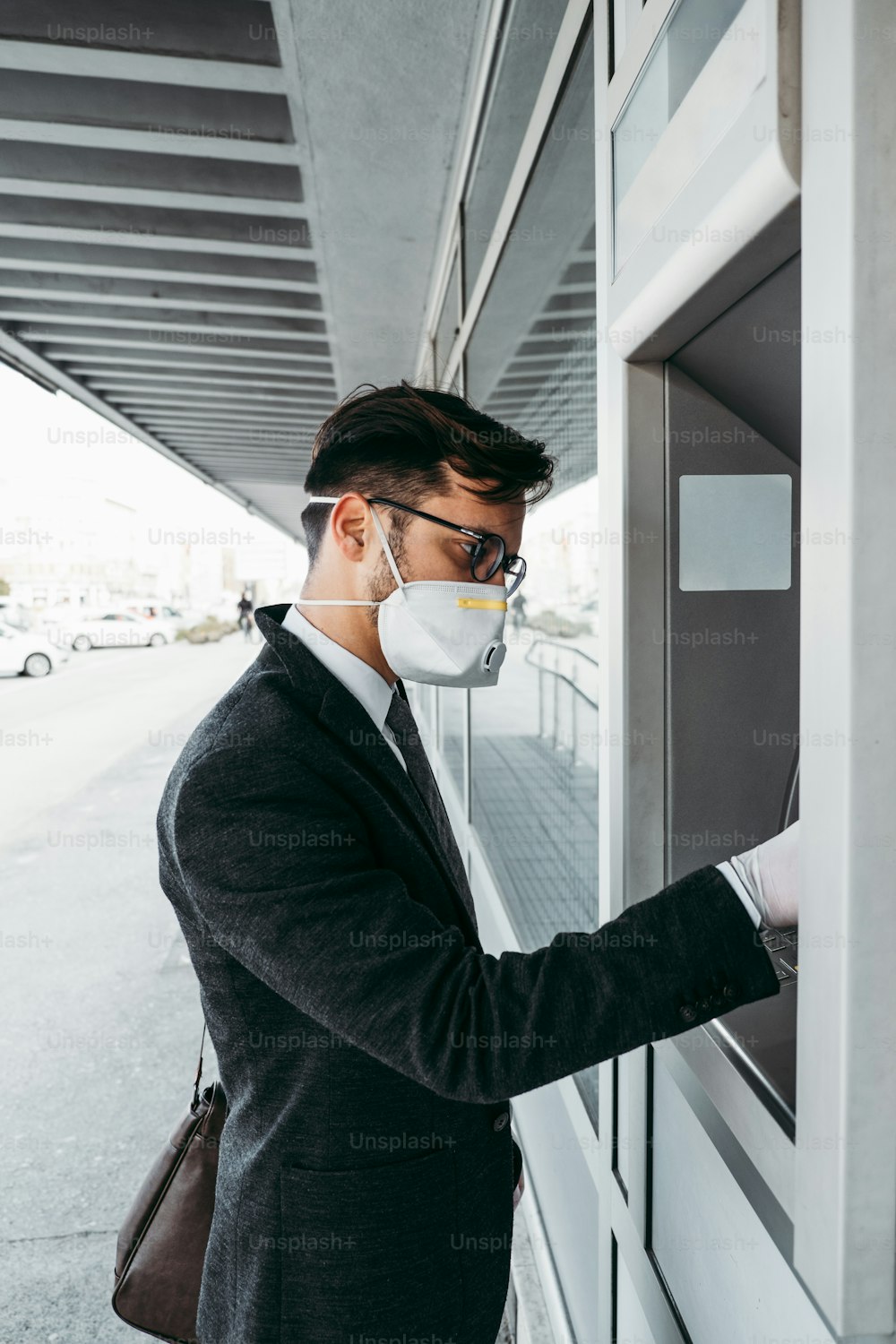 Business man with protective face mask and gloves using street ATM machine. Virus pandemic or epidemic concept.