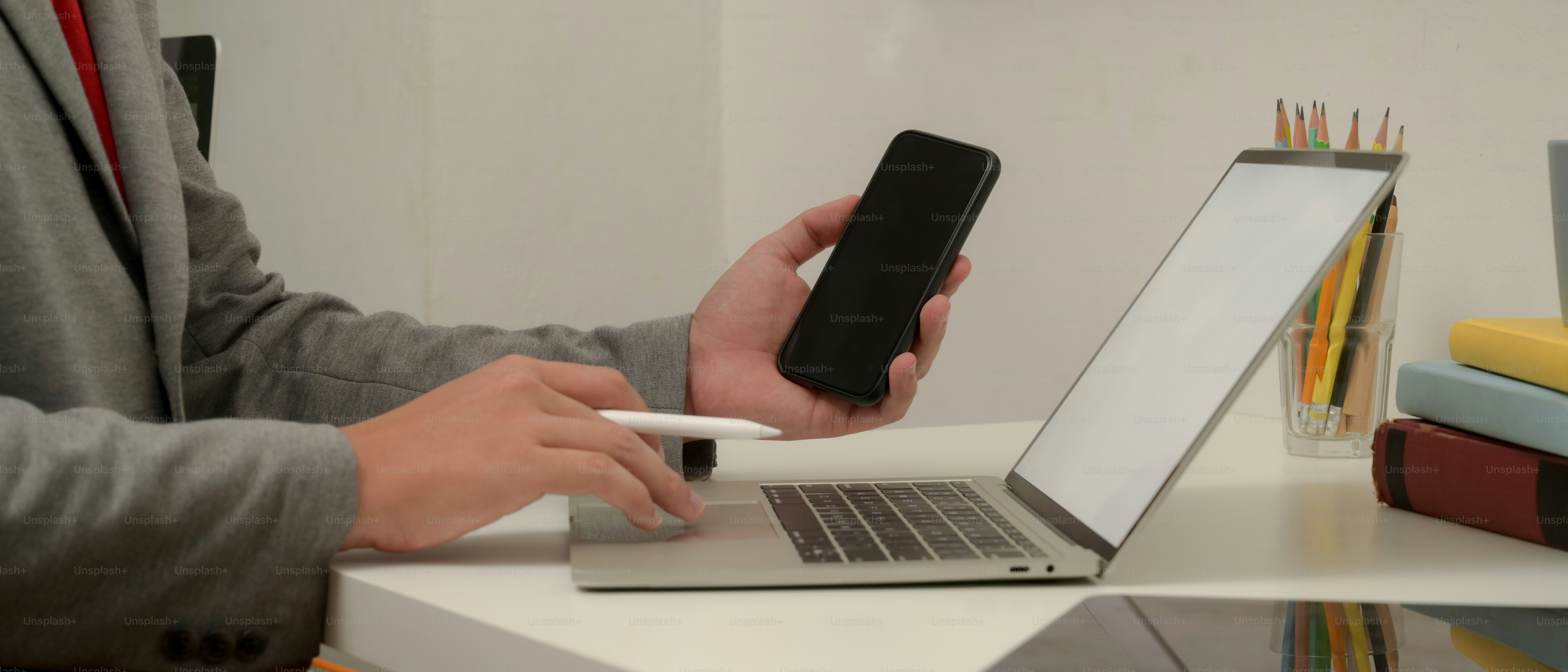 Side view of male worker working with mock up laptop and smartphone on worktable with supplies
