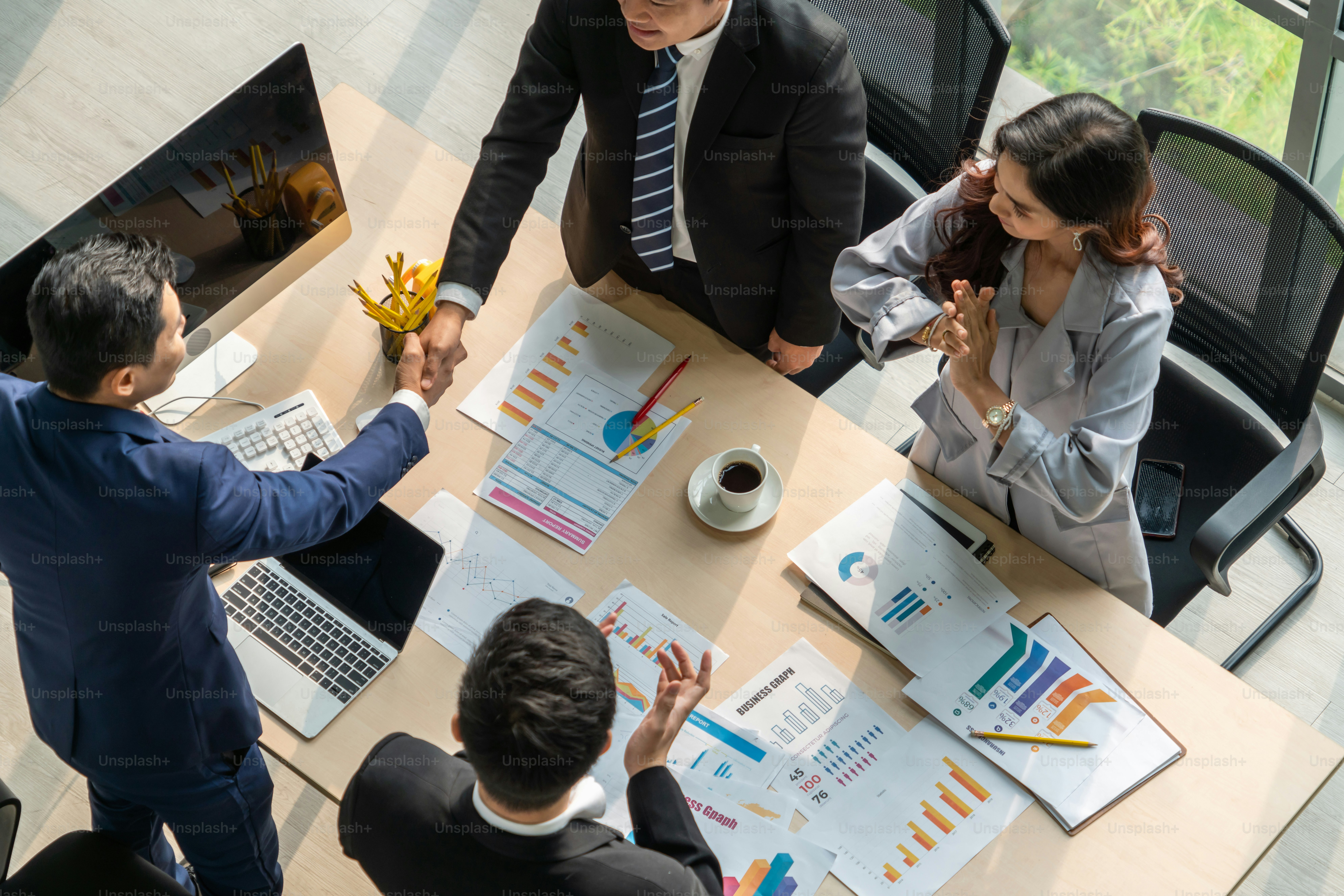 Group business people handshake at meeting table in office together with confident shot from top view . Young businessman and businesswoman workers express agreement of investment deal.