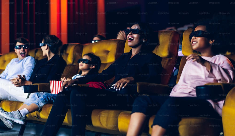 사람들의 그룹은 화면을 보고 흥미를 가지고 영화관에서 3D 안경으로 영화를 보고, 흥분하고 팝콘을 먹습니다.