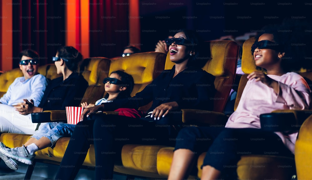 Groupe de personnes regarder un film avec des lunettes 3D dans une salle de cinéma avec intérêt en regardant l’écran, excitant et mangeant du pop-corn