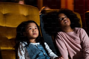 Dos niños africanos y asiáticos que se divierten y disfrutan viendo películas en el cine