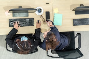 Business people wearing headset from top view in office working with computer to support remote customer or colleague. Call center, telemarketing agent service on telephone or video conference call.