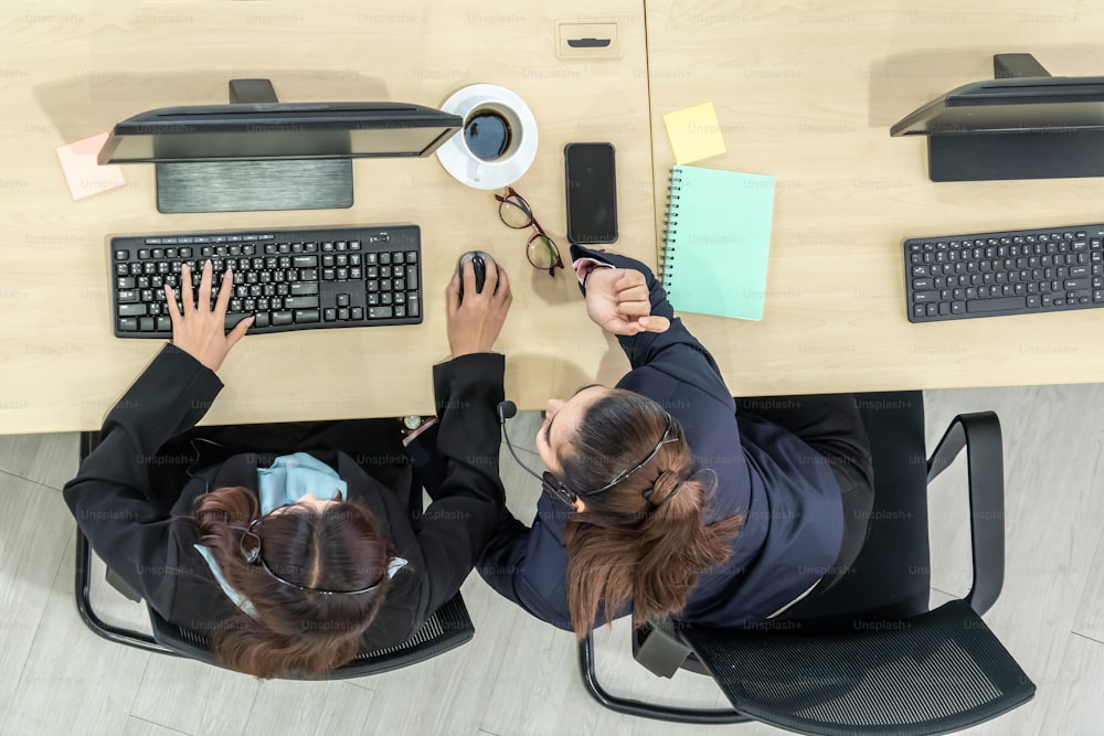 Des gens d’affaires portant un casque d’écoute de dessus au bureau travaillant avec un ordinateur pour soutenir un client ou un collègue à distance. Centre d’appels, service d’agent de télémarketing par téléphone ou vidéoconférence.
