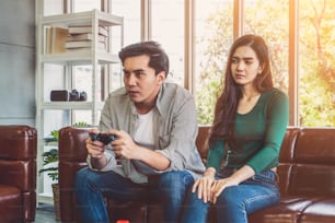 Young Asian couple suffers from computer games addiction. Family problem concept.