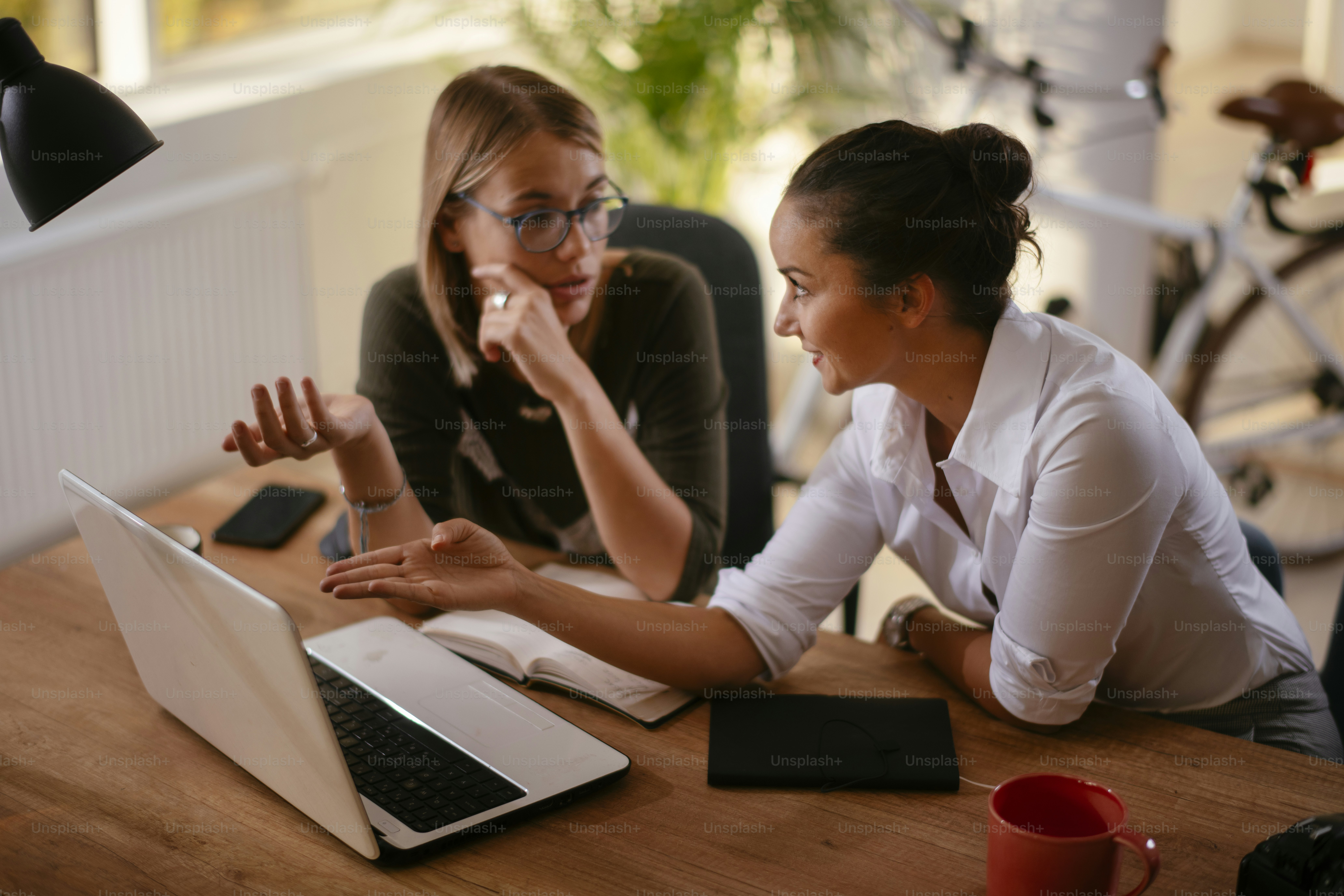 Duas colegas felizes discutindo trabalho. Empresárias que trabalham no escritório.