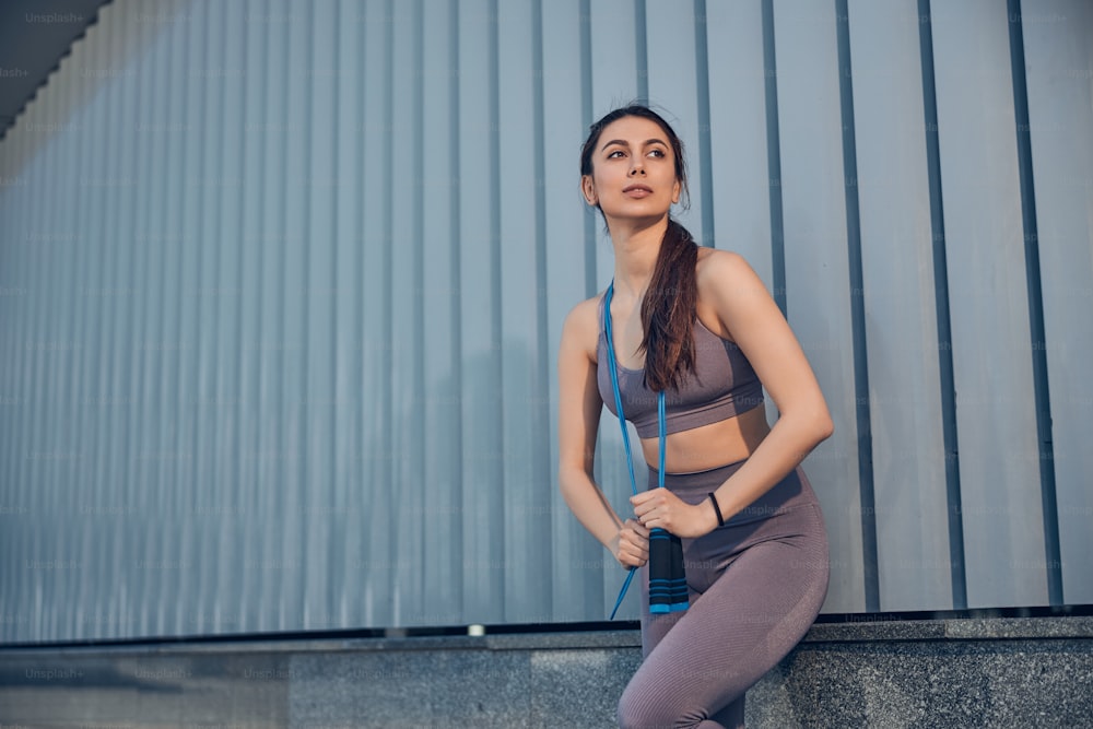 Front view of a serene fit young Caucasian female in active wear leaning against the wall