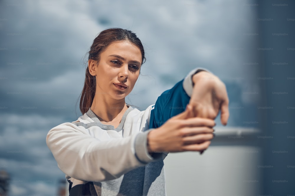 Portrait of a calm young Caucasian woman focusing on her hands during the outdoor workout