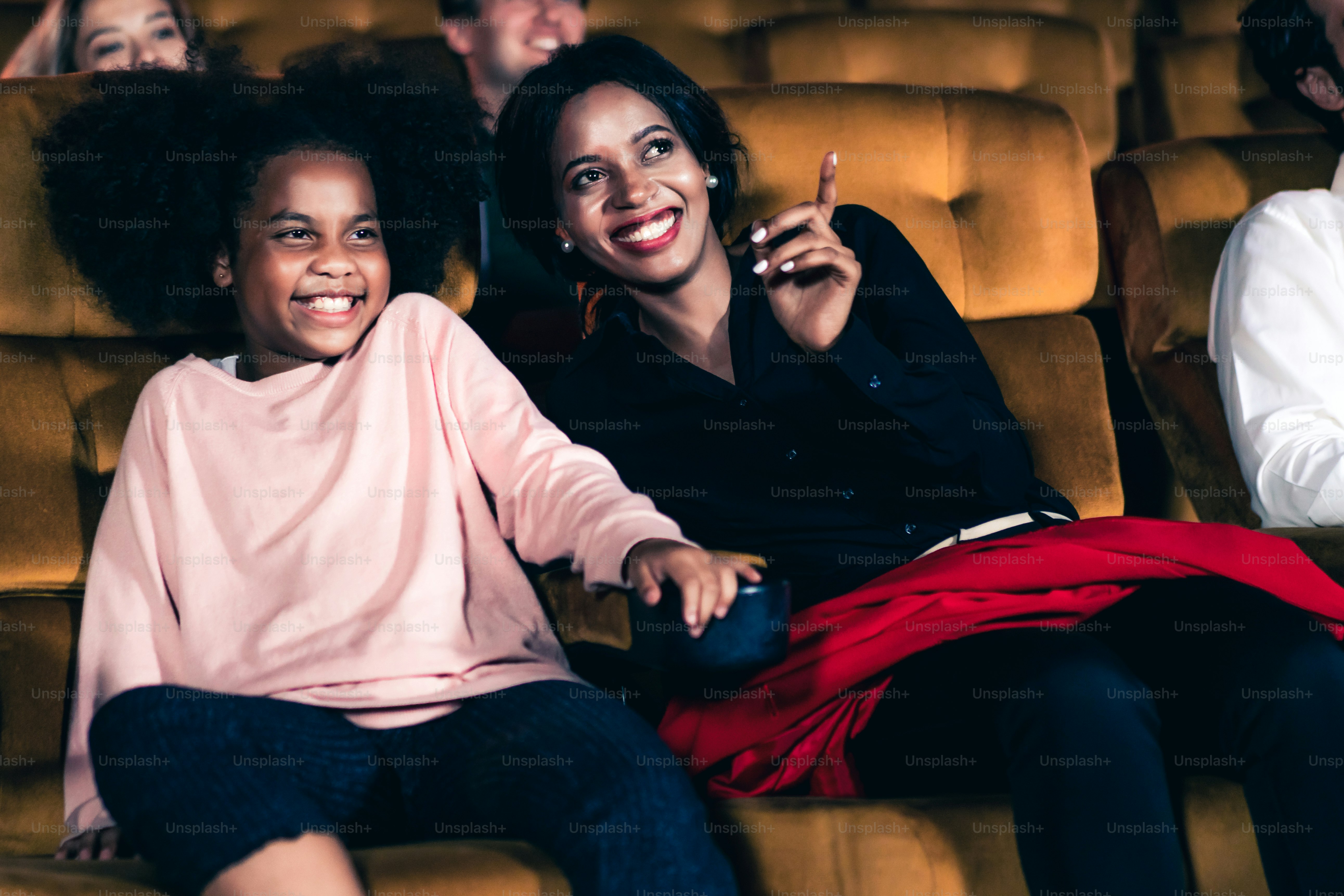 Woman enjoy to watch a movie with her daughter at the cinema smiling and laughing together