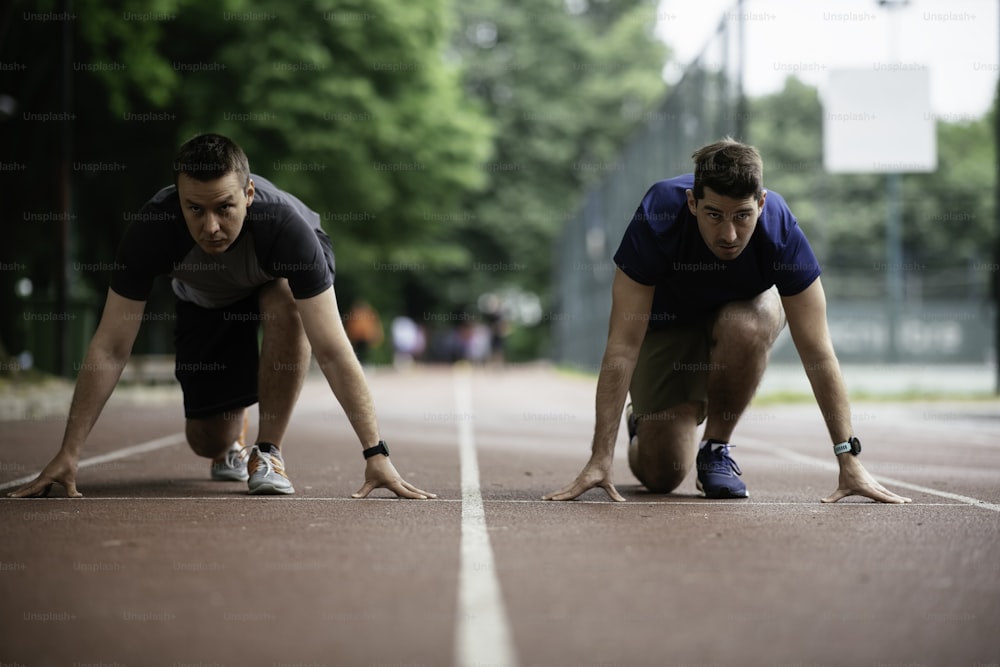 Young men training on a race track. Two young friends running on athletics track