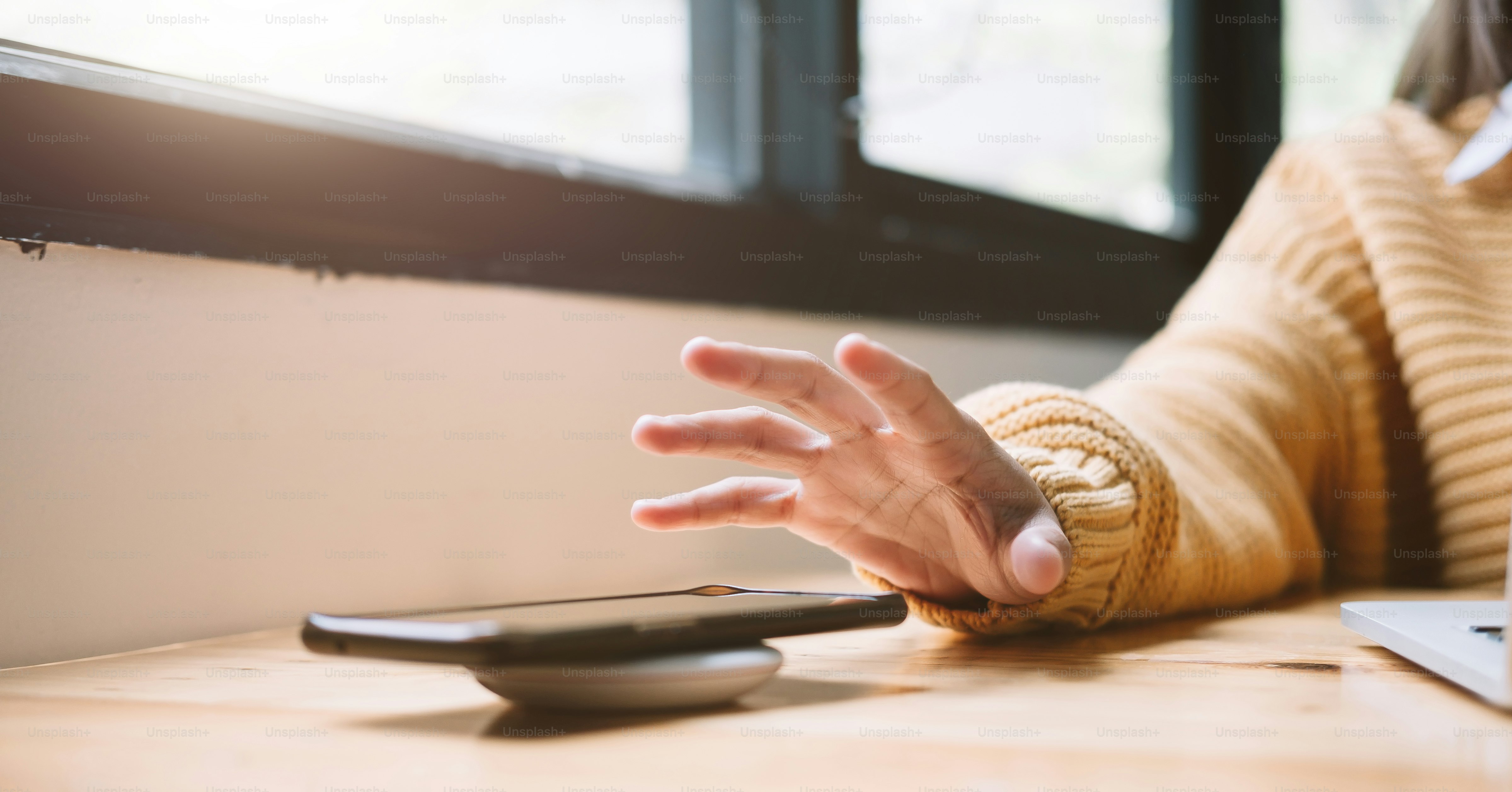 Woman Charging Smartphone Using Wireless Charging Pad At Home.
