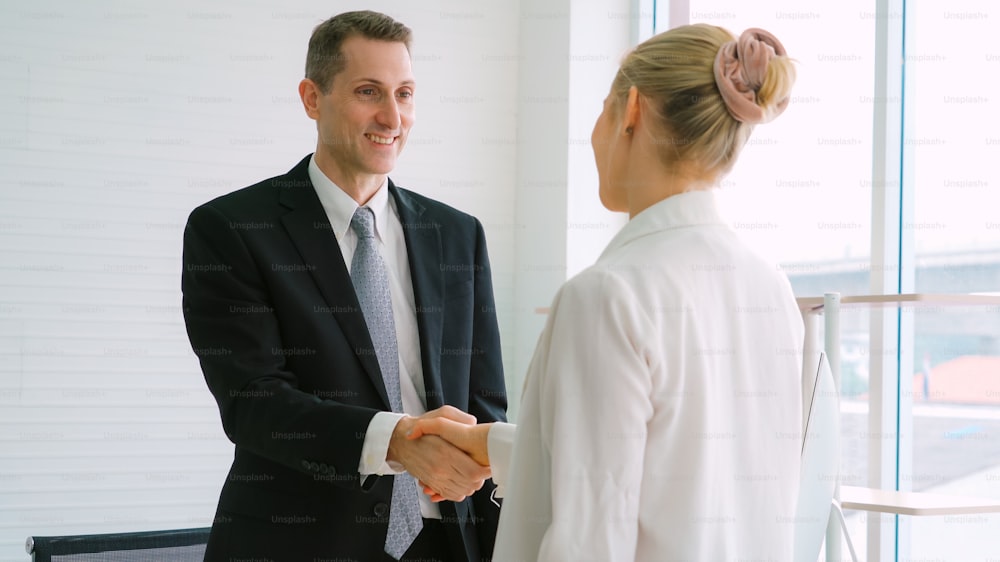 Business people handshake in corporate office showing professional agreement on a financial deal contract.