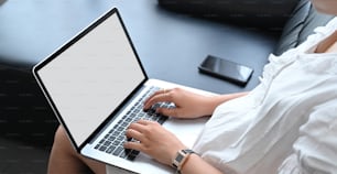 Beschnittene Bildhände benutzen ein Computer-Tablet auf dem schwarzen Ledersofa.
