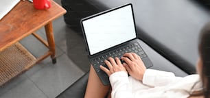 Las manos de imágenes recortadas están usando una tableta de computadora en el sofá de cuero negro.