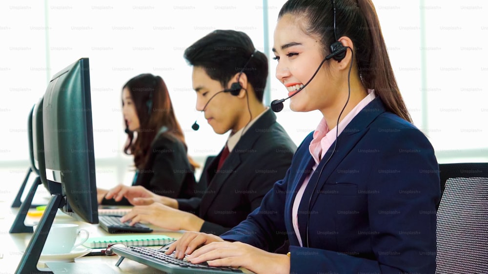 Personas de negocios que usan auriculares que trabajan en la oficina para apoyar a clientes o colegas remotos. El centro de llamadas, el telemarketing y el agente de atención al cliente brindan servicio en llamadas telefónicas de videoconferencia.