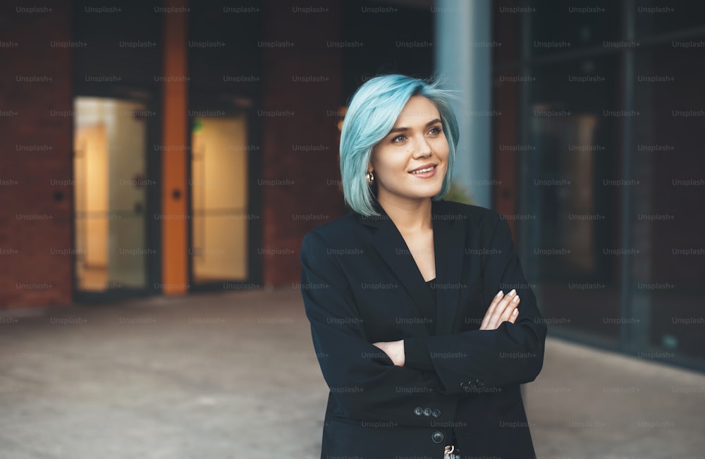 Caucasian entrepreneur with blue hair posing outside with crossed hand and smile