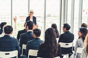 Group of business people meeting in a seminar conference . Audience listening to instructor in employee education training session . Office worker community summit forum with expert speaker .